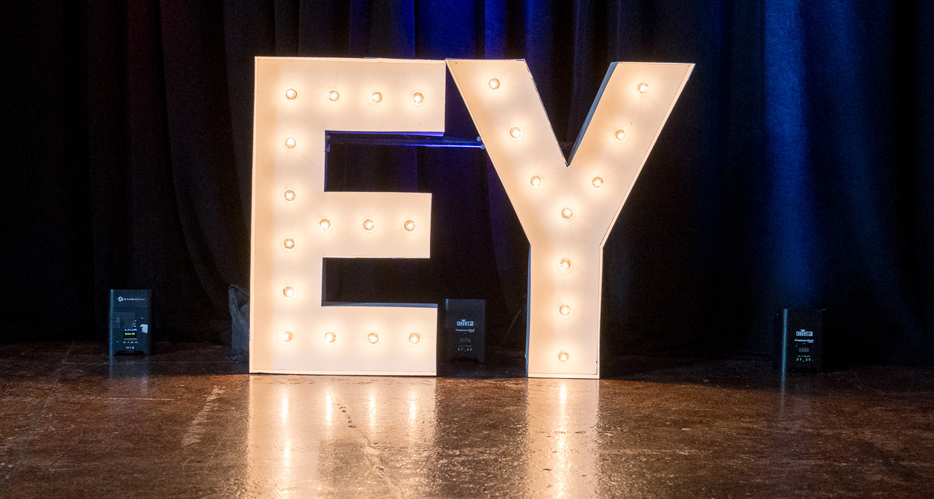 Lit up letters that spell "EY" against a dark blue background